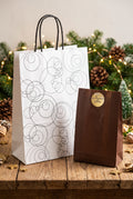 Sac cadeau blanc à motifs de cercles noirs et anses noires.
